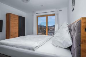 ein weißes Schlafzimmer mit einem Bett und einem Fenster in der Unterkunft Ferienhäuser Buchenweg in Bodenmais