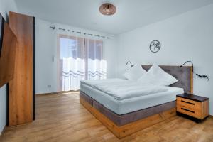 a white bedroom with a bed and a night stand at Ferienhäuser Buchenweg in Bodenmais