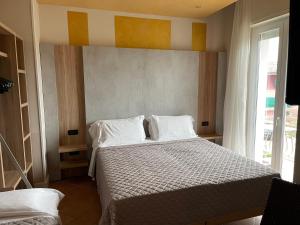 een slaapkamer met een bed met witte kussens en een raam bij Hotel Villa Rosa in Sirmione