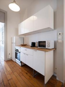 a kitchen with white appliances and a wooden floor at L'Annexe de Stanislas in Nancy