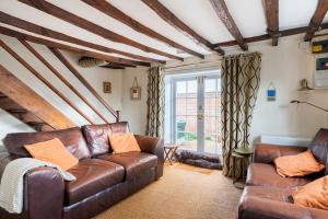 a living room with a leather couch and a window at Annex to Berry Cottage 2 Bedroom Cottage in Bramfield