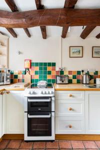 een keuken met witte kasten en een fornuis met oven bij Annex to Berry Cottage 2 Bedroom Cottage in Bramfield