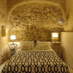 um quarto com uma cama e uma parede de pedra em Farmhouse Dhyana em Għasri