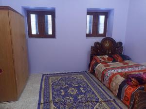 a bedroom with two beds and a rug and windows at Khodrey ka in Aswan