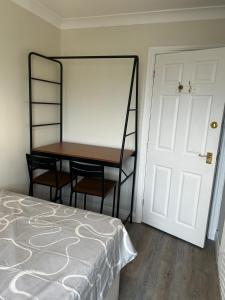 a bedroom with a bed and a desk next to a door at Private room in family home in Iford