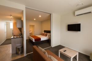 a hotel room with a bed and a television at Ramada Suites by Wyndham Christchurch City in Christchurch