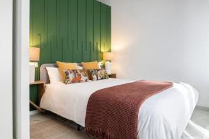 1 dormitorio con 1 cama grande y pared verde en Magno Apartments Hernando Colón en Sevilla