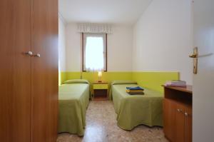 a small room with two beds and a window at Appartamenti Cocai, Acquaverde in Bibione