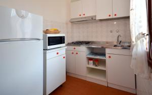 a kitchen with a white refrigerator and a microwave at Appartamenti Cocai, Acquaverde in Bibione