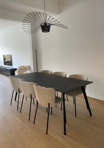 una mesa de comedor negra con sillas y una lámpara de araña en Cosy Apartment near Antwerp, en Mortsel