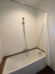 e bagno con vasca bianca e tenda doccia. di Cosy Apartment near Antwerp a Mortsel