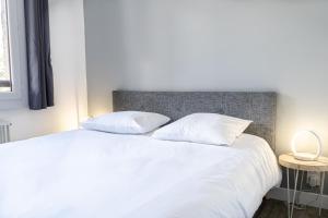 a bedroom with a white bed with two pillows at Les Anémones 6 places in Les Orres
