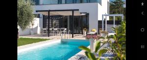 a swimming pool in front of a house with an umbrella at Villa Superior Two in Crikvenica