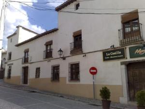 um edifício branco com janelas e um sinal de stop em Casas Recuero em Chinchón