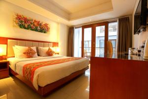 a hotel room with a bed and a desk and window at Bali Sun Tropical Hotel & Spa - formerly The Sun Hotel & Spa Legian in Legian
