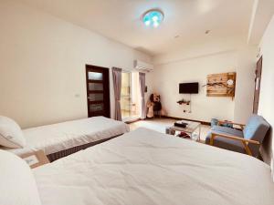 a hotel room with two beds and a tv at Xinzhan 23 B&B in Taitung City