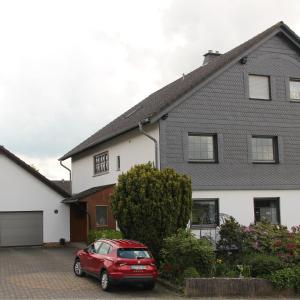 a red car parked in front of a house at Ferienwohnung Mietzner in Laubach