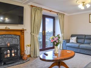 a living room with a fireplace and a blue couch at Scalelands Cottage in Frizington