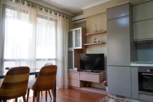 Lovely apartment in the heart of Tirana في تيرانا: مطبخ مع كرسيين وتلفزيون في الغرفة