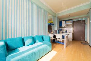 RedLiving Apartemen The Suites Metro - Prisma في باندونغ: غرفة معيشة مع أريكة زرقاء ومطبخ