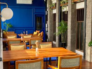 un restaurante con mesas y sillas de madera y una pared azul en Umpadhi Canggu, en Canggu