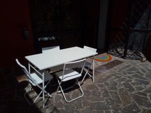 uma mesa branca e cadeiras sentadas no chão em la tana nel bosco em Durazzano