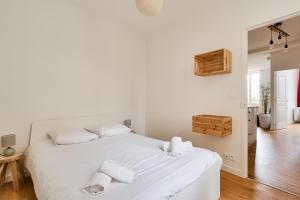 Un dormitorio blanco con una cama blanca con toallas. en Plein centre de Nantes, appartement pour 4 en Nantes