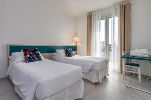 a hotel room with two beds and a window at Appartamenti Villa Campo Rosso in Colà di Lazise