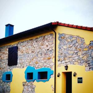 a yellow building with a stone wall at Albergue Casa Vacas in Carriazo