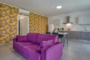 a purple couch in a living room with a kitchen at Appartamenti Villa Campo Rosso in Colà di Lazise