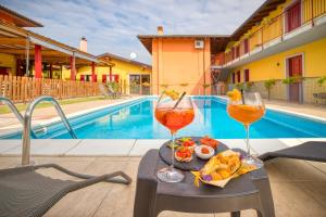 twee glazen wijn en eten op een tafel naast een zwembad bij Appartamenti Villa Campo Rosso in Colà di Lazise