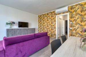 salon z fioletową kanapą i stołem w obiekcie Appartamenti Villa Campo Rosso w mieście Colà di Lazise
