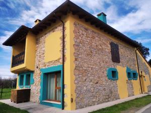 a small house with yellow and blue paint at Albergue Casa Vacas in Carriazo