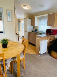 a kitchen and dining room with a wooden table at Older Style Caravan Pebble Bank T10 in Wyke Regis
