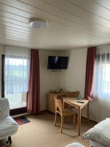 Habitación con mesa y TV en la pared. en Hotel-Pension- Vesperstube Waldblick en Mainhardt