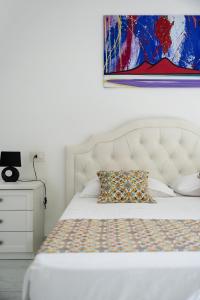 een wit bed met een kussen en een schilderij aan de muur bij Deluxe Suites in Piano di Sorrento