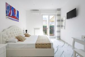 een witte slaapkamer met een bed en een televisie bij Deluxe Suites in Piano di Sorrento