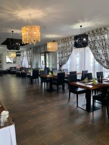 a dining room with tables and chairs and chandeliers at Grand hotel/pension in Sládkovičovo