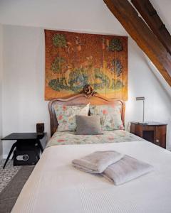 ein Schlafzimmer mit einem weißen Bett mit Wandteppich in der Unterkunft Panorama sur le Château de Carrouges in Carrouges
