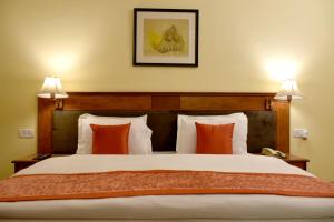 um quarto com uma cama grande e almofadas laranja em Greenwood Hotel em Khajuraho