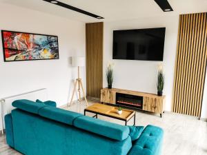 ein Wohnzimmer mit einem blauen Sofa und einem TV in der Unterkunft NOVA House Apartments in Delniţa