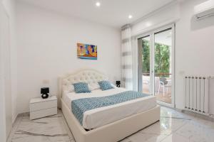 een witte slaapkamer met een groot bed en een balkon bij Deluxe Suites in Piano di Sorrento