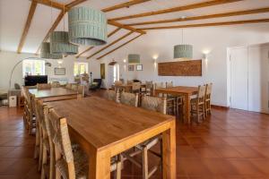 uma sala de jantar com mesas e cadeiras de madeira em Quinta Marugo Retreats em Serpa