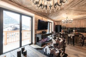 uma sala de estar com um lustre e uma cadeira e uma cozinha em Belvedere Elite em Canazei