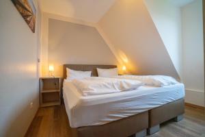 - un lit avec des draps et des oreillers blancs dans l'établissement Haus Nordseetraum Wohnung 5, à Büsum