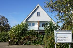 une maison blanche avec un panneau devant elle dans l'établissement Haus Nordseetraum Wohnung 5, à Büsum