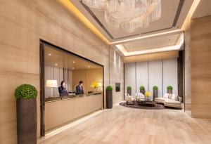 a lobby of a hotel with two people in a mirror at Somerset Grandview Shenzhen in Shenzhen