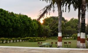 une table et des chaises dans un parc arboré dans l'établissement Greenwood Hotel, à Khajurâho