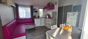 małą kuchnię z fioletową kanapą i stołem w obiekcie mobil-home 6 places w mieście Biscarrosse