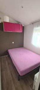 duże różowe łóżko w pokoju z oknem w obiekcie mobil-home 6 places w mieście Biscarrosse
